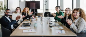 Personas trabajando y sonriendo durante una reunión en la oficina, transmitiendo bienestar y ambiente positivo