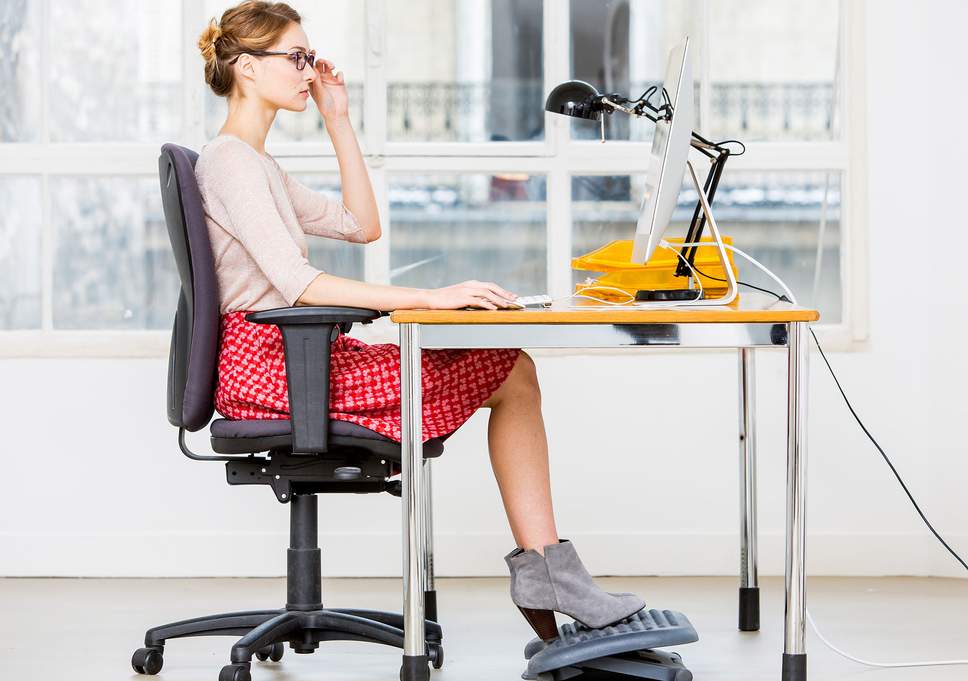 Mujer sentada en su escritorio con una postura ergonómica correcta frente al ordenador