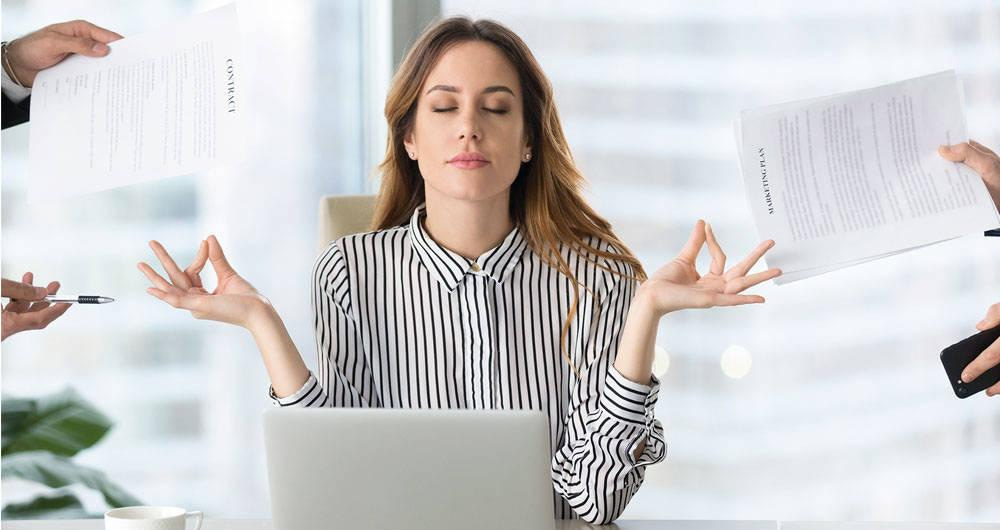 Mujer meditando con los ojos cerrados en su escritorio de oficina