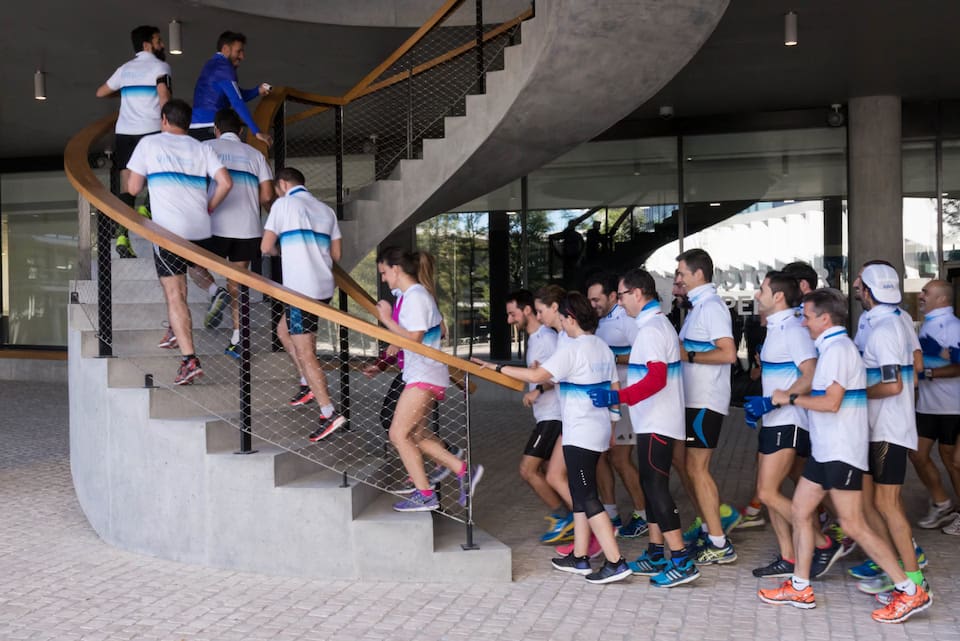 Grupo de empleados subiendo escaleras exteriores mientras corren en equipo