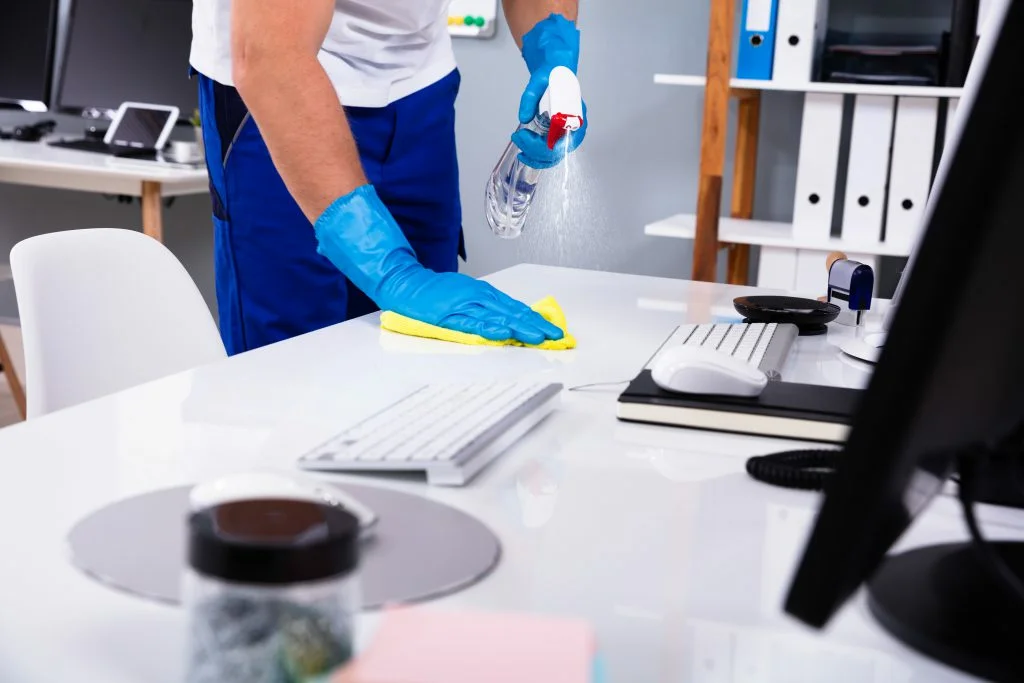 Limpieza de escritorio con productos desinfectantes en oficina