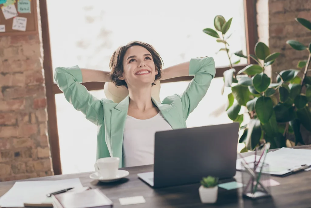 Mujer sonriente disfrutando del aire fresco en una oficina con plantas