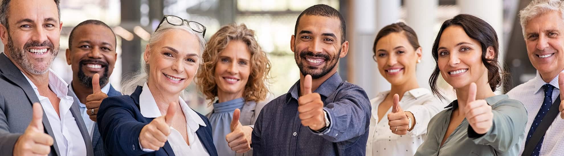Grupo de personas diversas sonriendo y mostrando el pulgar hacia arriba