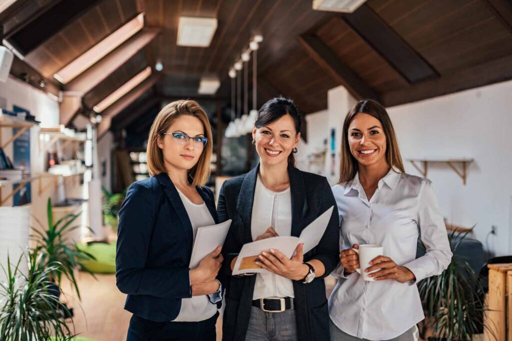 Tres mujeres profesionales sonrientes en una oficina moderna